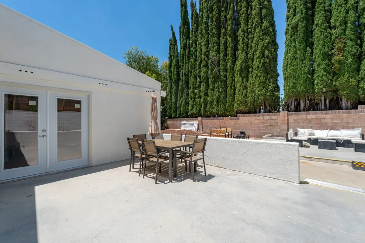 Back patio with outdoor dining set framed by tall cypress trees