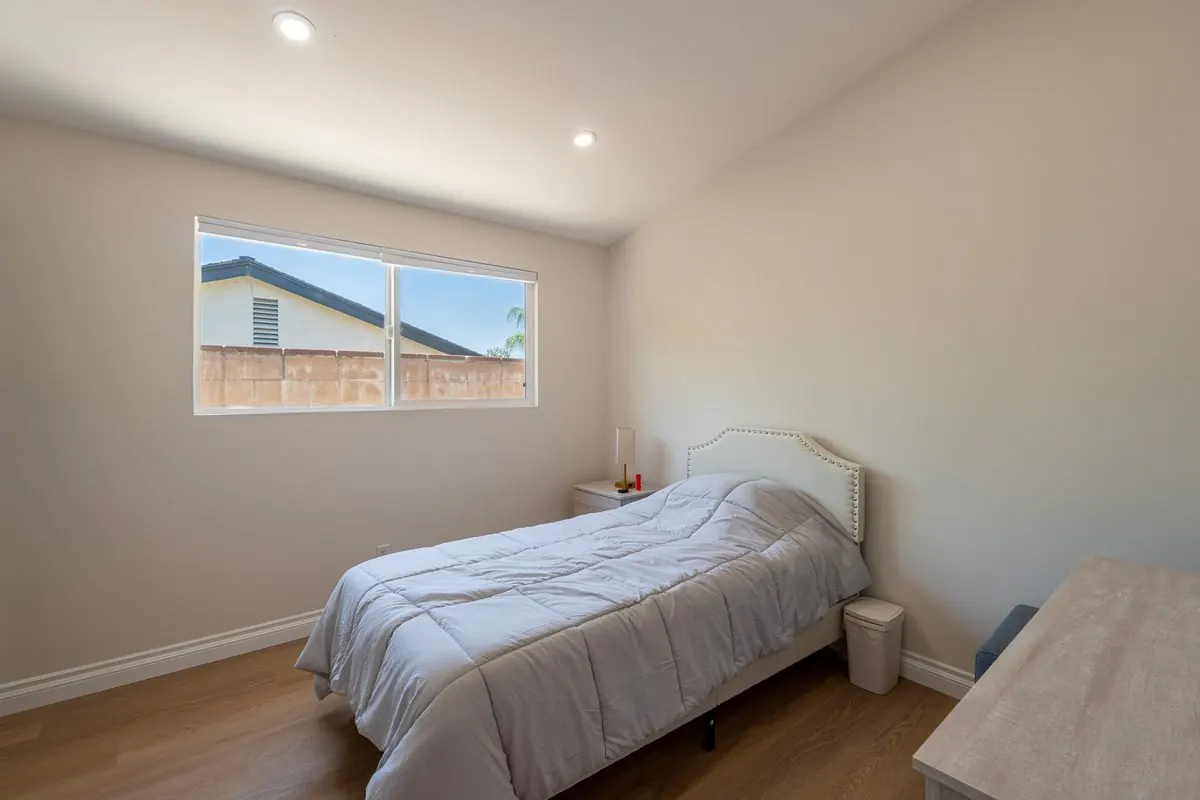 Sunlit private bedroom with an upholstered bed and wood floors