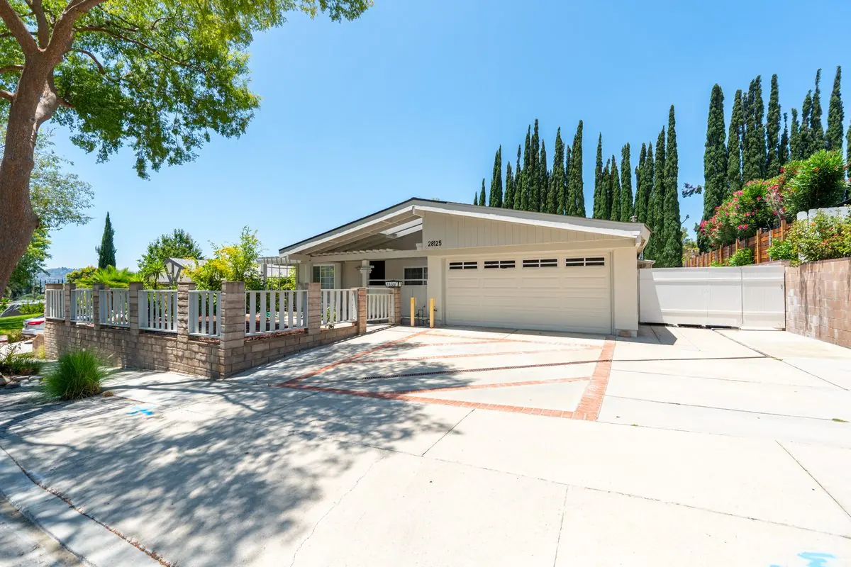 Front exterior of the care home with a white fence and tall cypress trees