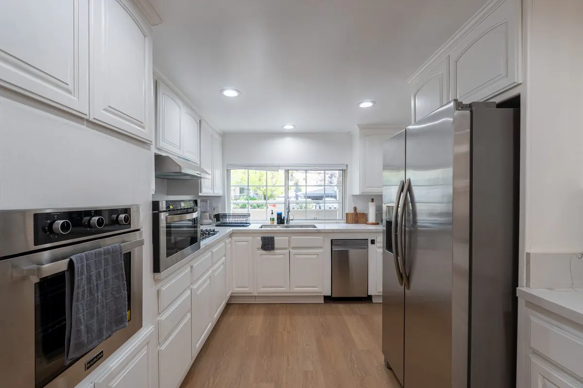 White kitchen with stainless steel appliances and a garden window